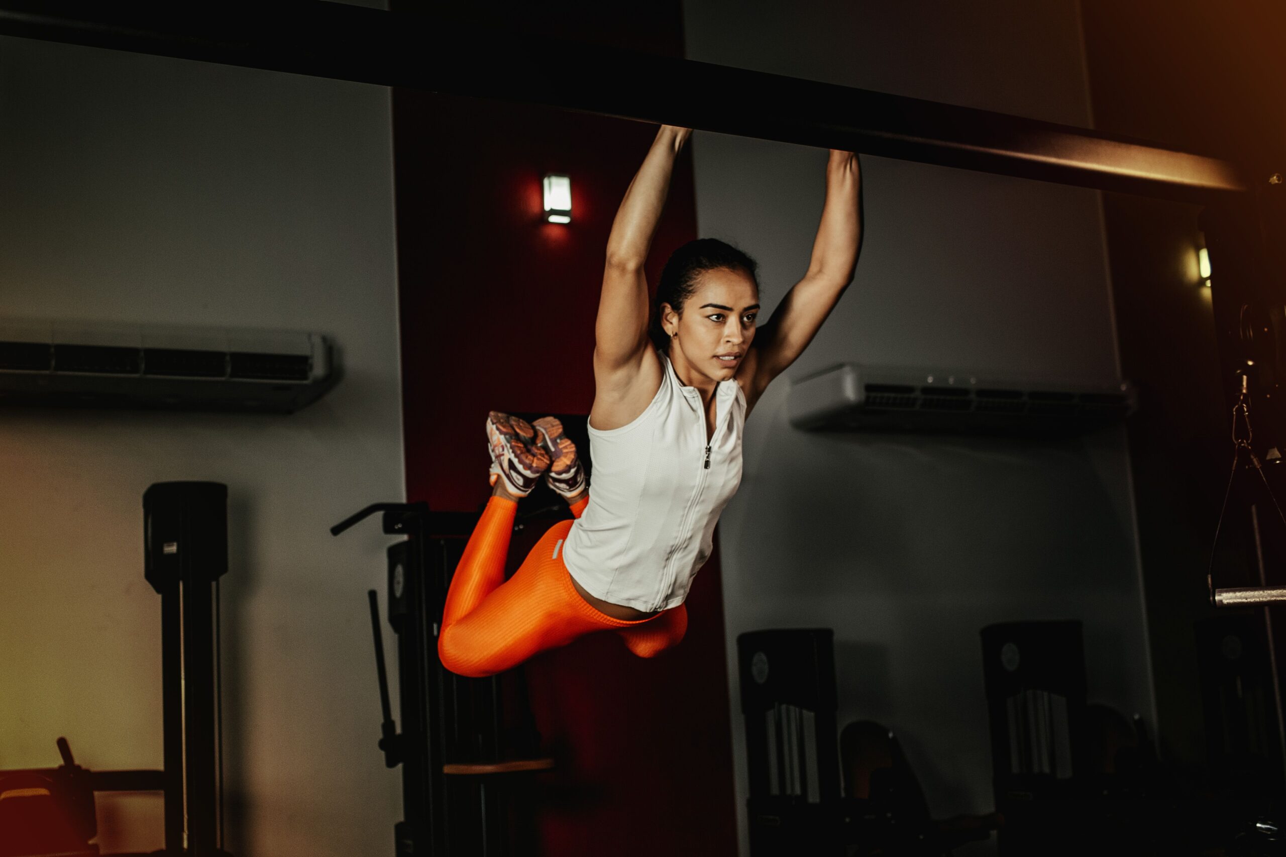 Strong woman in athletic wear executing a pull-up exercise indoors.