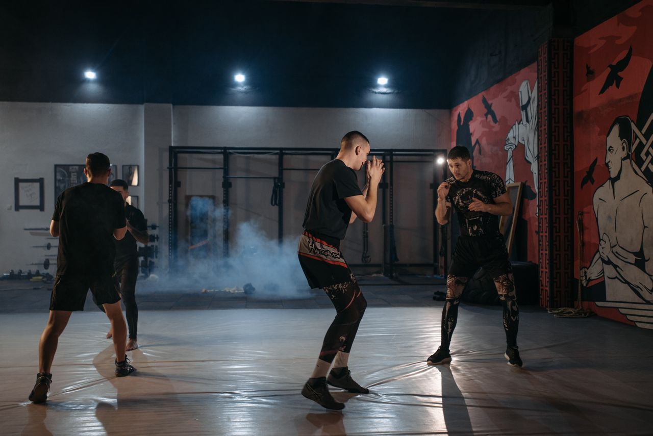 Intense martial arts training with four athletes sparring indoors.